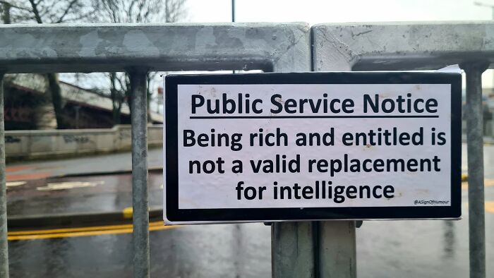 An absurd sign on a metal fence giving a public service notice about being rich and entitled.