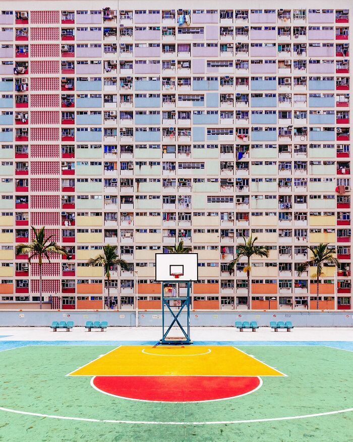 A photographer captures a perfectly composed image of a colorful apartment building with a basketball court in front.