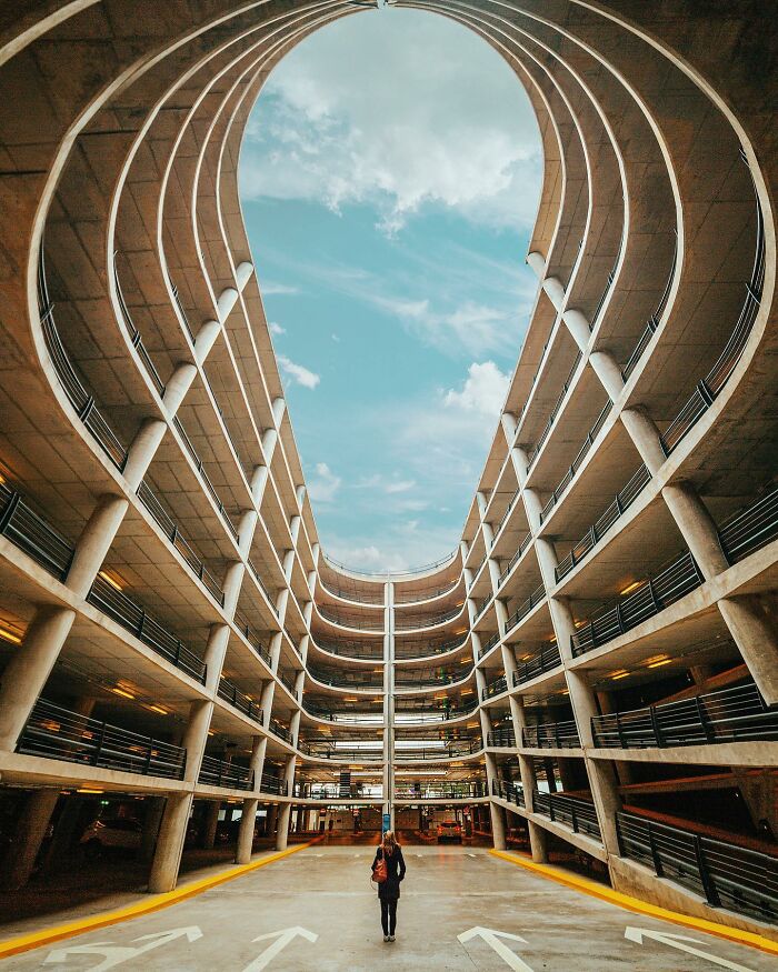 Architectural locations, a large circular concrete parking garage with a person standing in the middle.