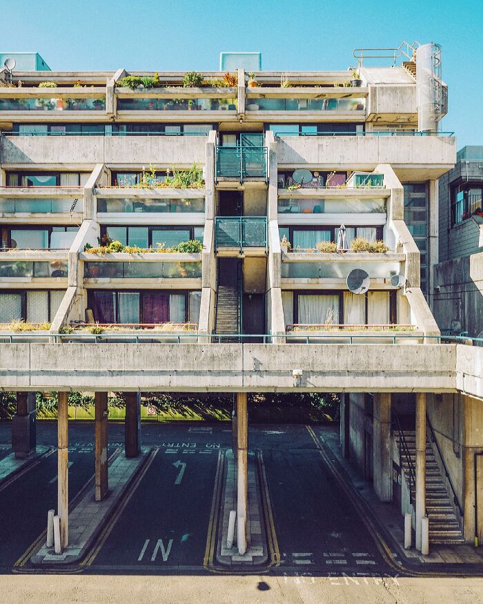 Brutalist architectural building with stacked concrete sections and green plants on balconies, showing architectural locations.