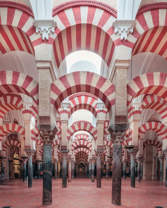 A photographer captures the grand interior of a historic hall with red and white striped arches, a must-see architectural location.