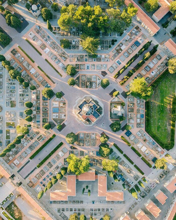 An aerial view of a cemetery designed in a symmetrical pattern with trees, an intriguing architectural location.