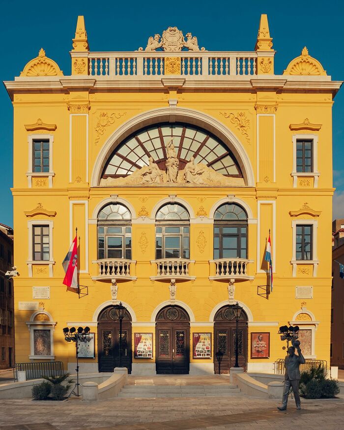 A vibrant yellow architectural building with classical details and a large arched window, highlighting architectural locations.