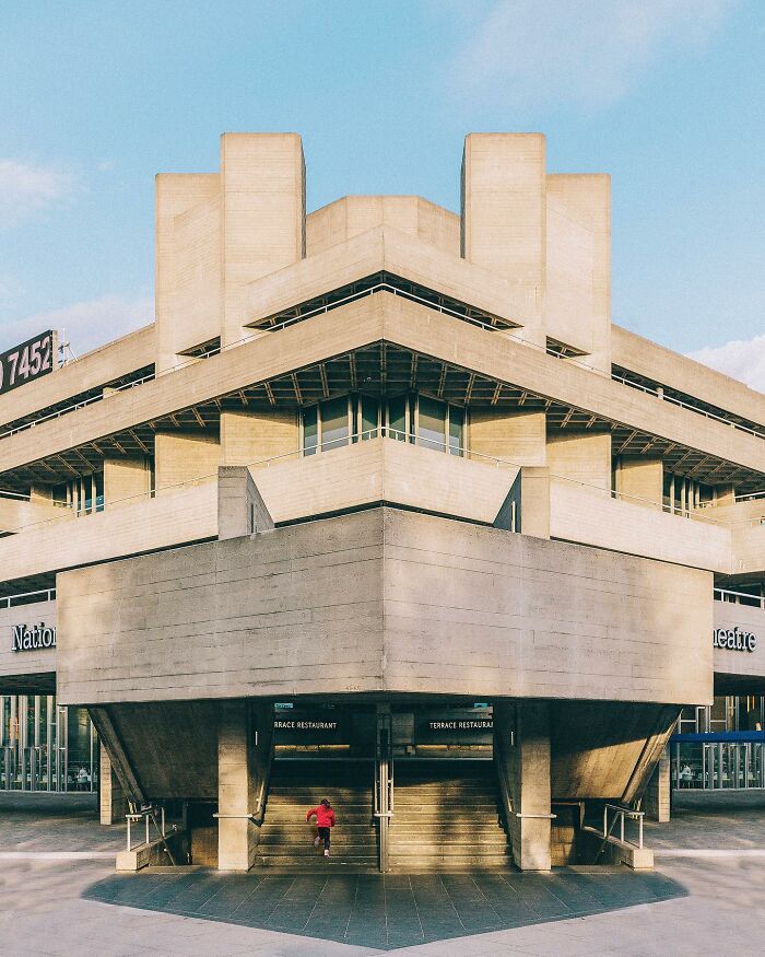 A person running up the stairs of a concrete Brutalist building, an architectural location.