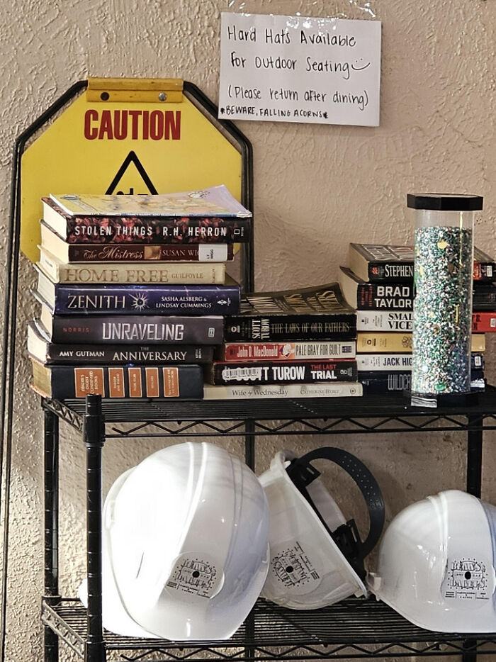 A surprisingly simple and genius idea, a shelf with a caution sign, books, and hard hats for outdoor seating.