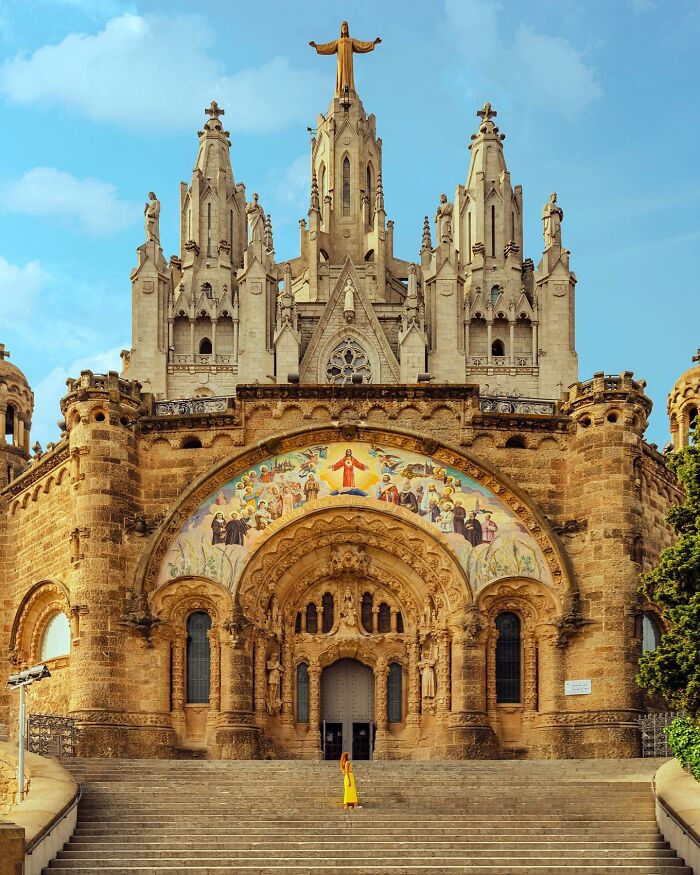 Architectural locations, a grand, ornate church with a golden statue on top, a woman in yellow approaches.