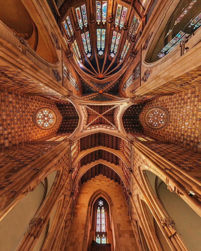 Looking up at a cathedral's high, vaulted ceiling with intricate patterns and stained glass, showcasing architectural locations.