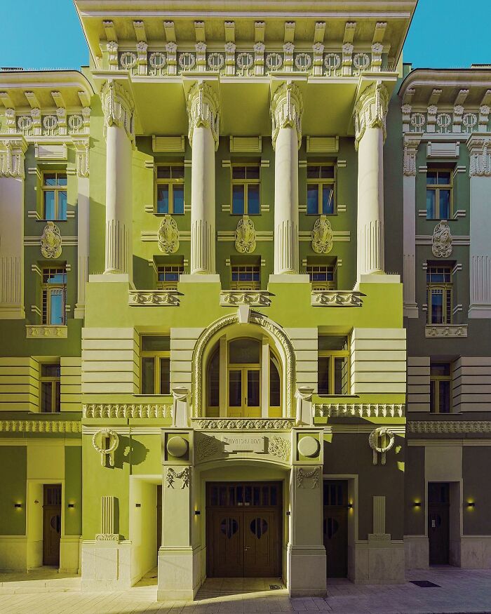 A photographer captures a perfectly composed image of a grand green architectural location with columns and detailed facade.