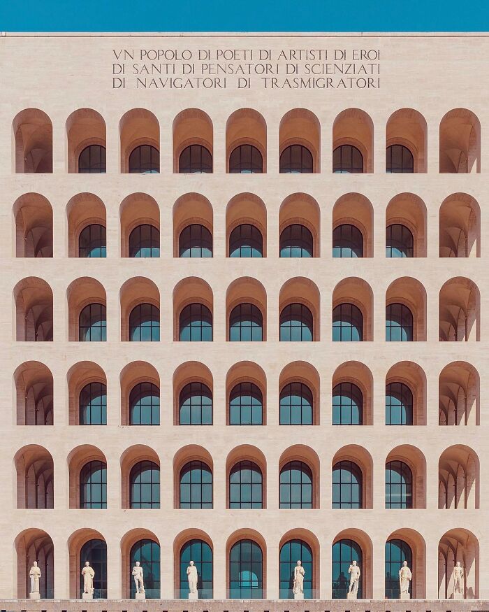 A photographer captures a perfectly composed image of a minimalist architectural building with many arches and statues.