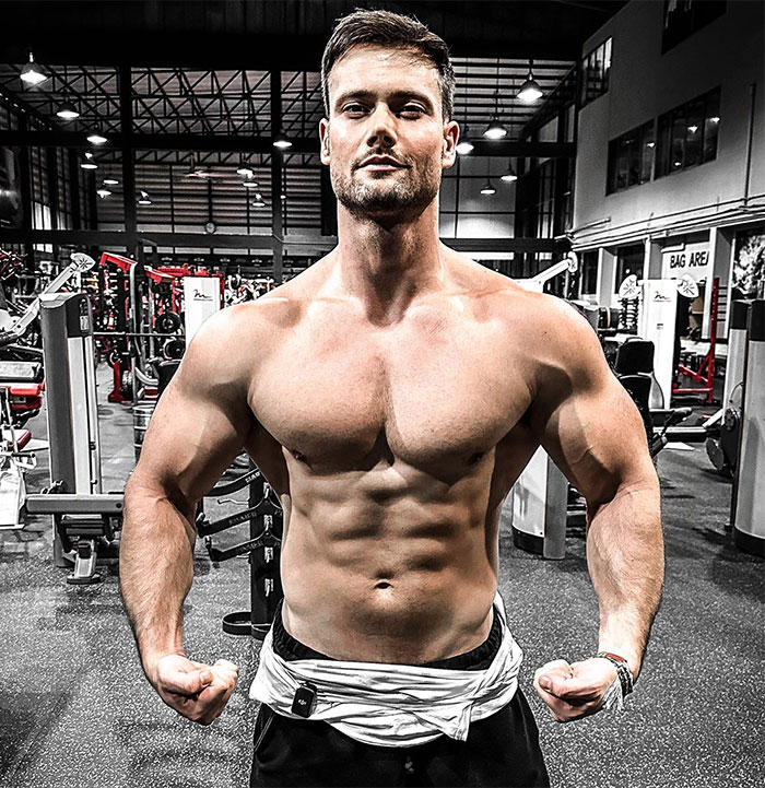 Looksmaxxer poses in a gym, showing his muscular physique, related to a bizarre incident.
