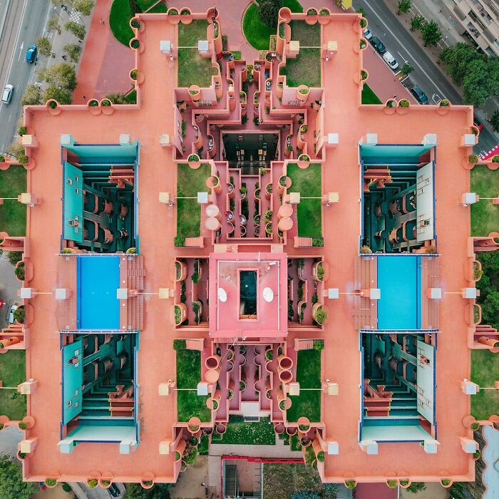 A photographer captures a perfectly composed image of a sprawling architectural complex with multiple pools and courtyards from an aerial view.