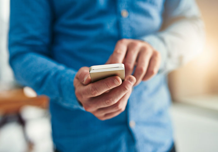 A man holds a smartphone, symbolizing a student worker calling in sick, as a lazy manager fires her.