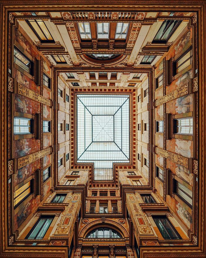 An upward view into an architectural location's ornate ceiling with a large glass skylight in the center.