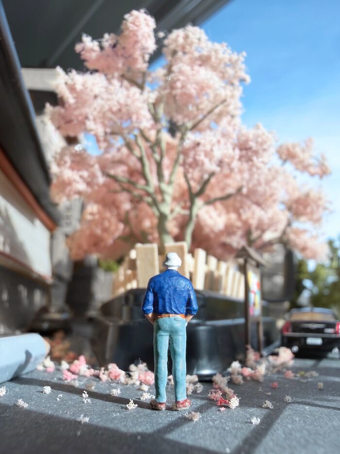 Artist Derrick Lin turns his office desk into intricate diorama sets, featuring a person observing a cherry blossom tree.