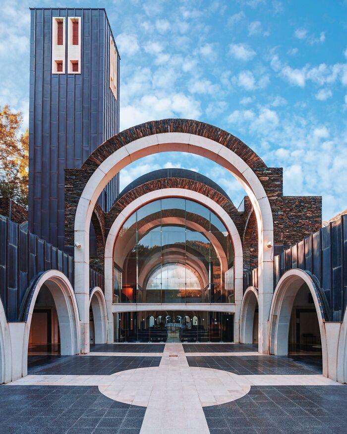 The grand entrance of a modern building with large archways and glass, a unique architectural location.