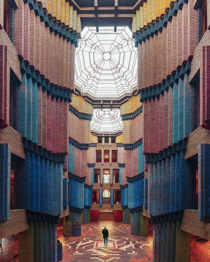 A photographer captures a grand interior architectural location with patterned brickwork and a domed skylight.