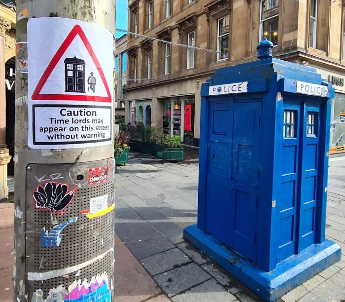 A brilliant absurd sign warning of Time Lords appearing, next to a blue police box.