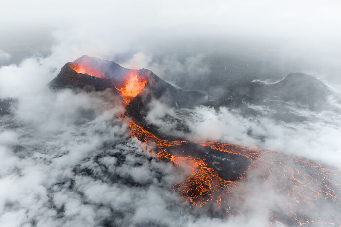 Spectacular aerial photo capturing an erupting volcano with glowing lava and smoke, awarded at the Aerial Photographer of the Year competition.