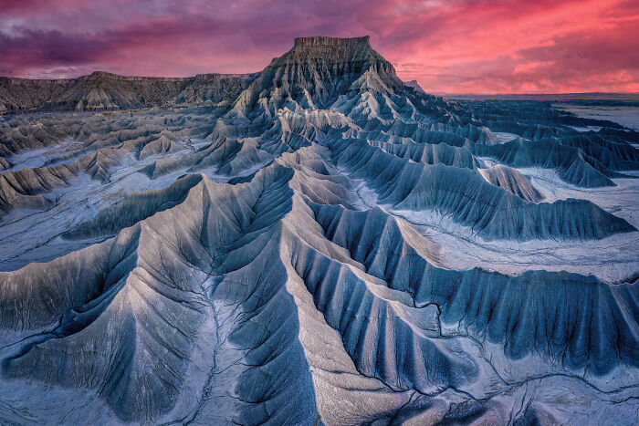 An aerial photograph of a vast, sculpted landscape under a vibrant pink and purple sky, awarded at the 2026 competition.