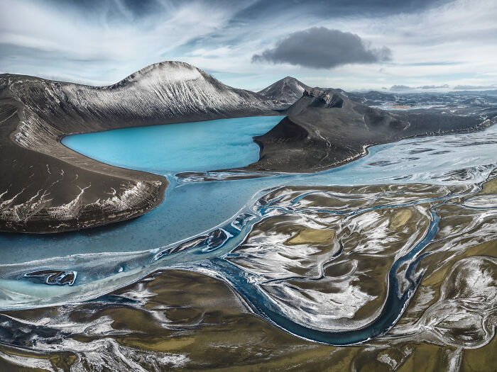 Breathtaking Aerial Photographer of the Year shot of a turquoise lake, mountains, and braided rivers.