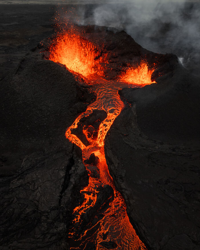 Spectacular aerial photograph of a vibrant lava flow from an erupting volcano, awarded at the Aerial Photographer of the Year competition.