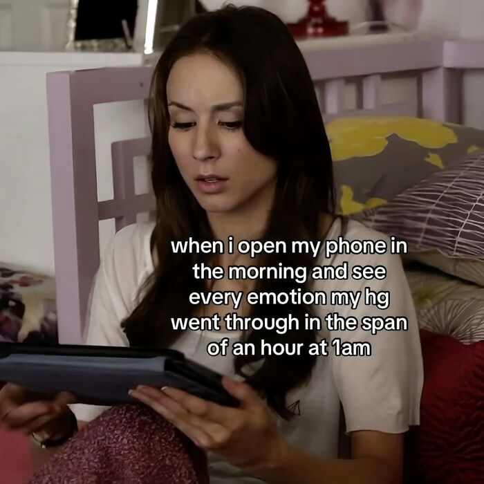 A woman looks intently at a tablet in bed, representing hilarious memes and relatable morning phone checks.
