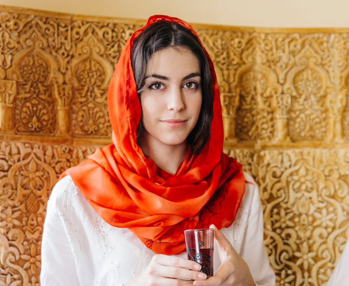 A woman, potentially a coworker, holding a small glass, looking at the camera, related to a story about being rejected. A woman, potentially a coworker, holding a small glass, looking at the camera, related to a story about being rejected.