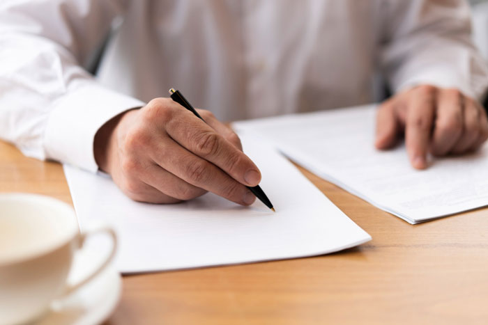 A close-up of a person's hands signing a document, related to the Saudi dad's Arctic tour refund request. A close-up of a person's hands signing a document, related to the Saudi dad's Arctic tour refund request.