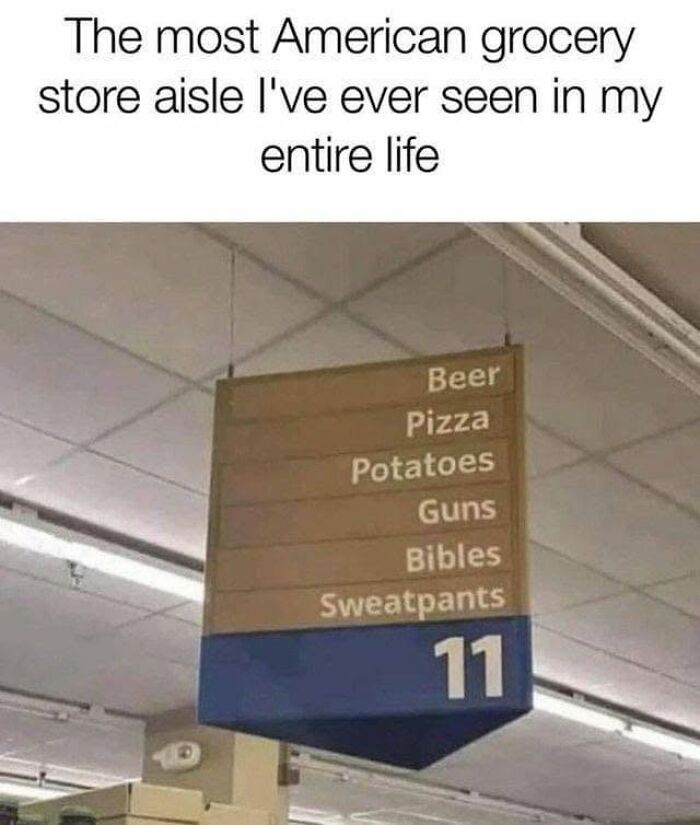 A grocery store aisle sign listing Beer, Pizza, Potatoes, Guns, Bibles, and Sweatpants, satirizing America's cultural decline into idiocy.