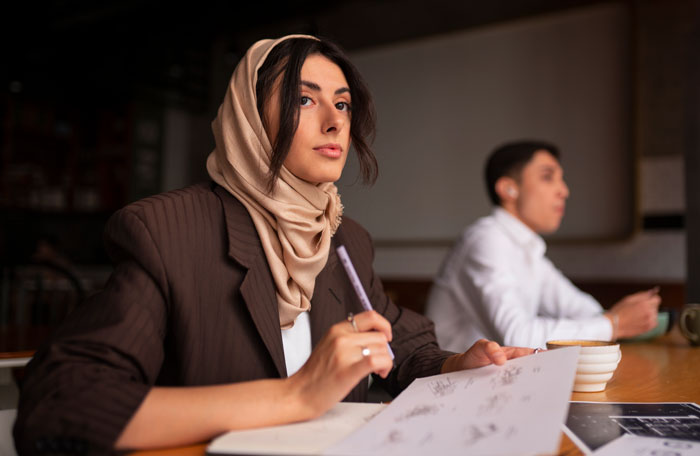 A thoughtful female coworker working in an office, focusing on her notes, rejecting advances. A thoughtful female coworker working in an office, focusing on her notes, rejecting advances.