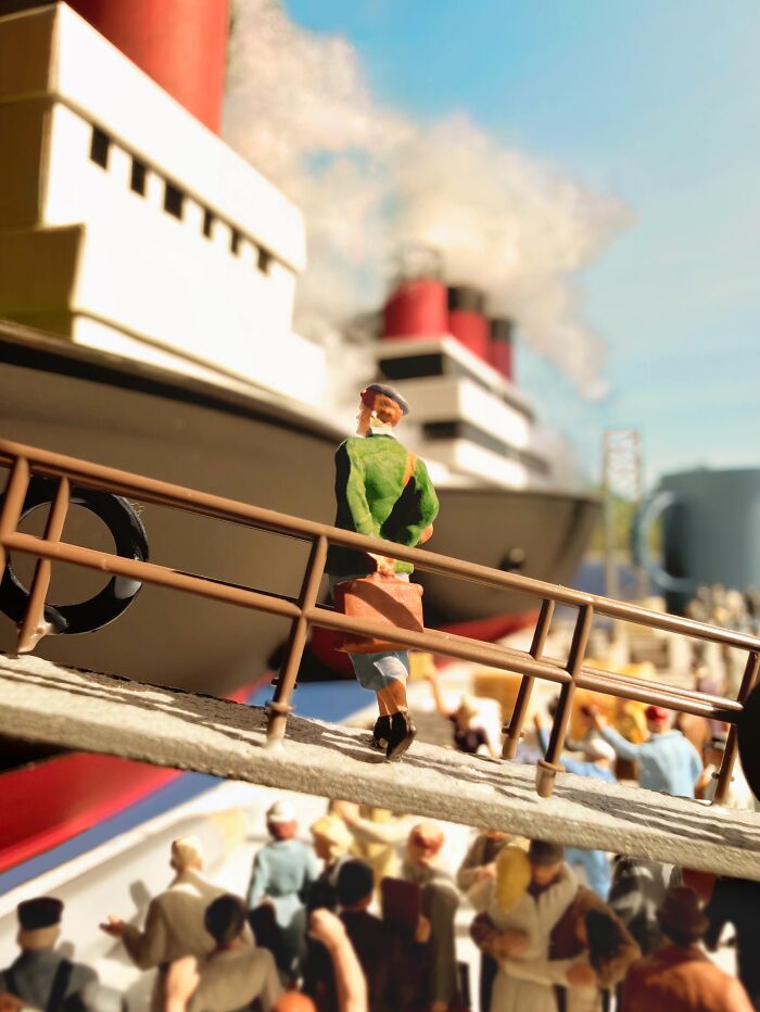 Artist Derrick Lin turns his office desk into intricate diorama sets, with a figure boarding a large ship at a bustling port.
