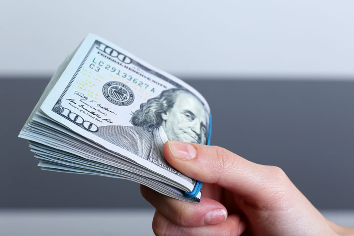 A hand holding a stack of hundred-dollar bills, representing the financial struggles of a Narcissist Mom. A hand holding a stack of hundred-dollar bills, representing the financial struggles of a Narcissist Mom.