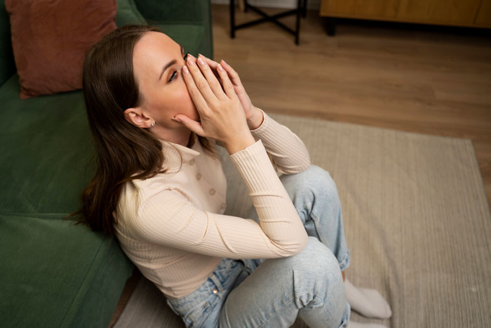 A distressed young woman, possibly the daughter, sitting on the floor, reflecting on the Narcissist Mom attack. A distressed young woman, possibly the daughter, sitting on the floor, reflecting on the Narcissist Mom attack.