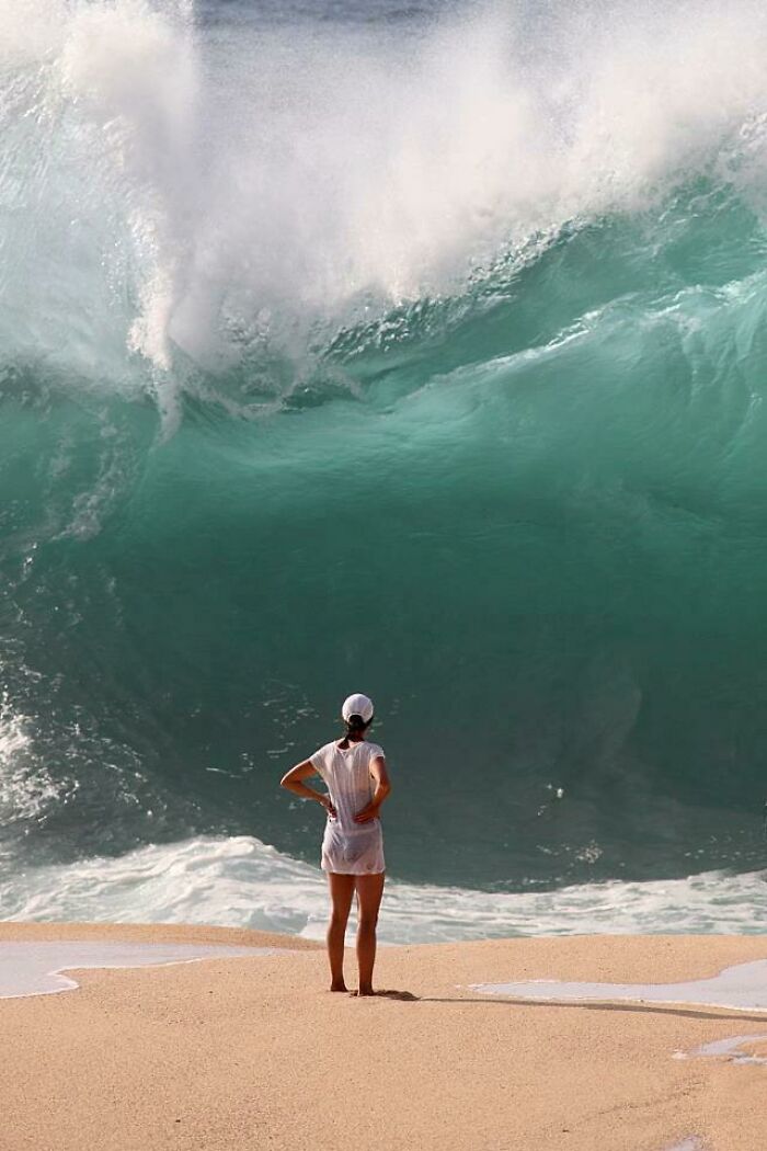 Hilarious photo of a woman standing on the beach as a massive wave crashes behind her moments before disaster struck.