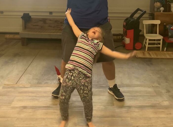 A girl throws her arms up and makes a funny face, captured moments before disaster.