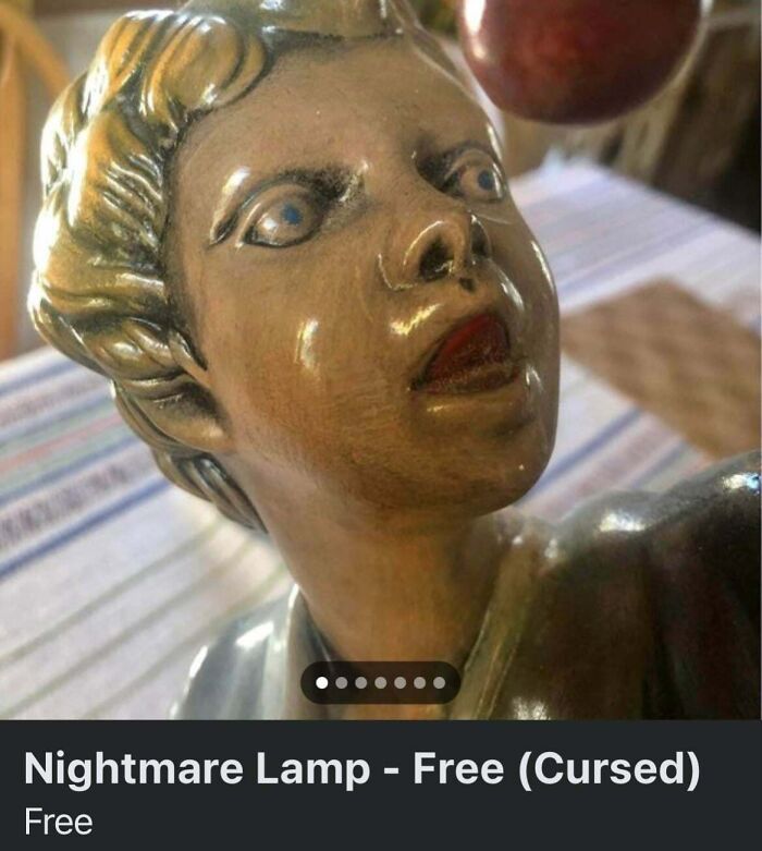 A creepy, antique-looking lamp featuring a child-like figure with an intense gaze, described as a cursed nightmare lamp in unhinged marketplace listings.