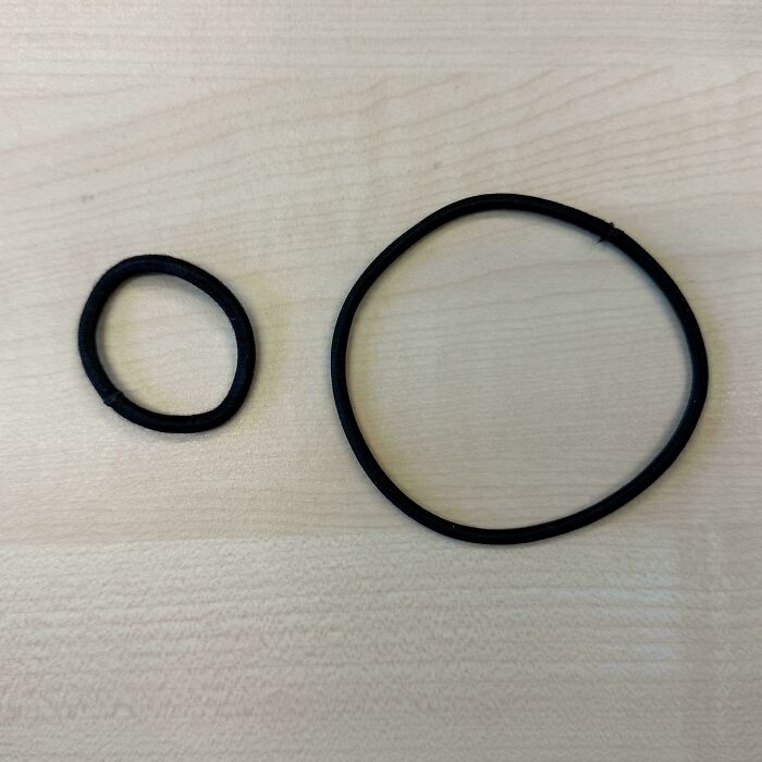 A new, small hair tie next to a stretched, old hair tie, showing before-and-after use and how much things can change.