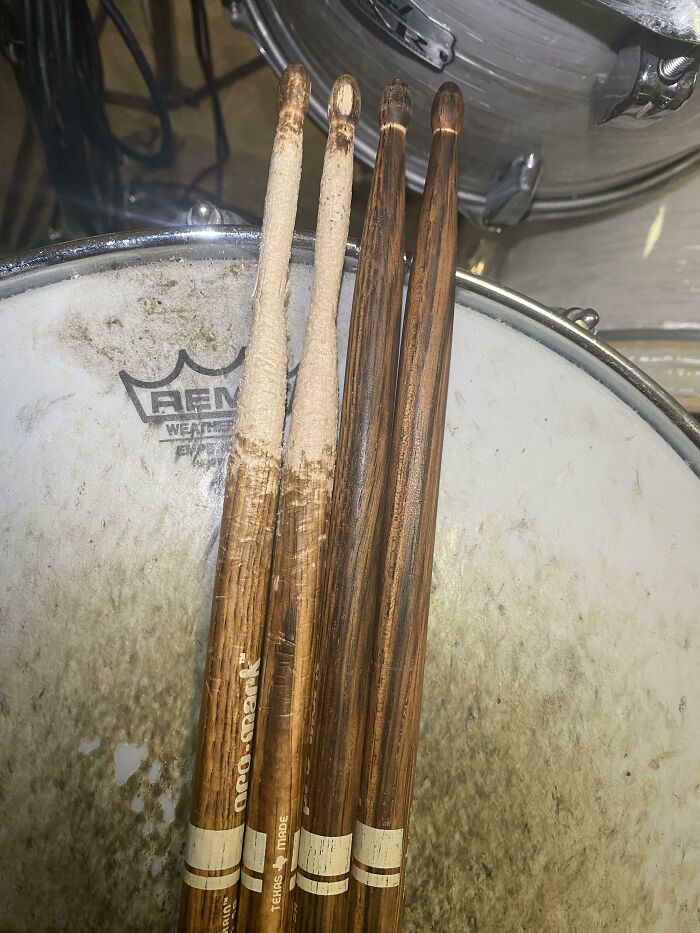 Before-and-after photo of two pairs of drumsticks showing the significant change from new to well-used.