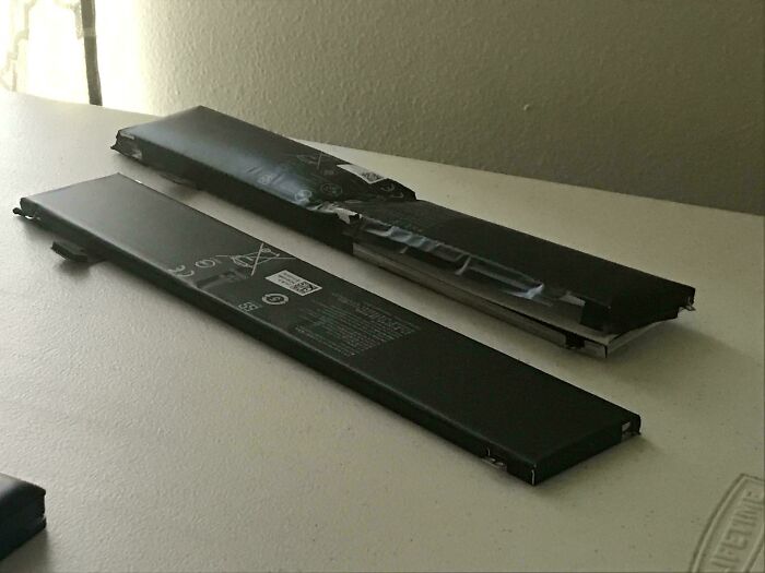 Before-and-after photo of a swollen laptop battery next to a new one, displaying how much things can change over time.