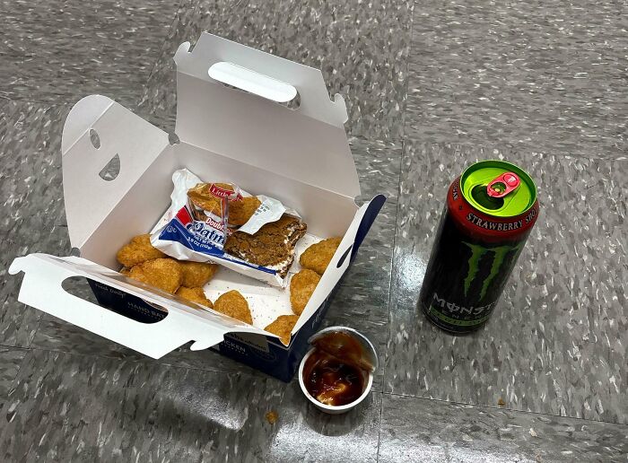 Entitled men's fast food mess: a discarded box of chicken nuggets, dessert, and a Monster energy drink on the floor.