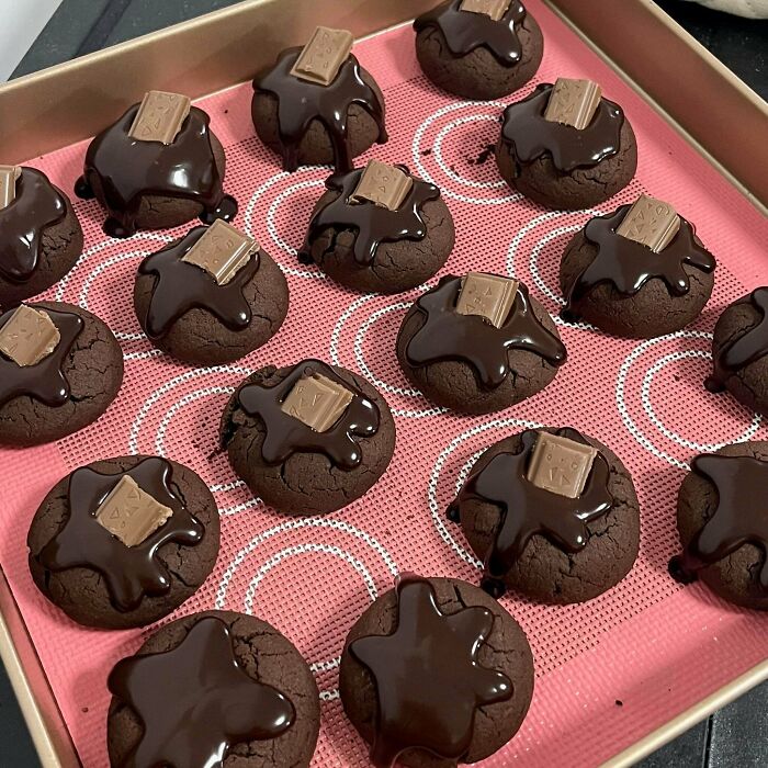 A tray of treats, dark chocolate cookies with melted chocolate and chocolate bar pieces.