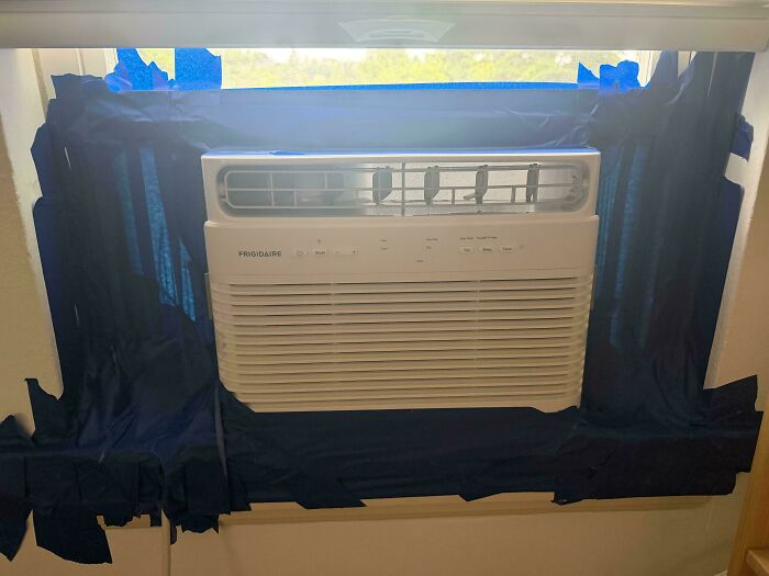 A window AC unit with fabric taped around it to seal gaps, a clever solution to improve efficiency.