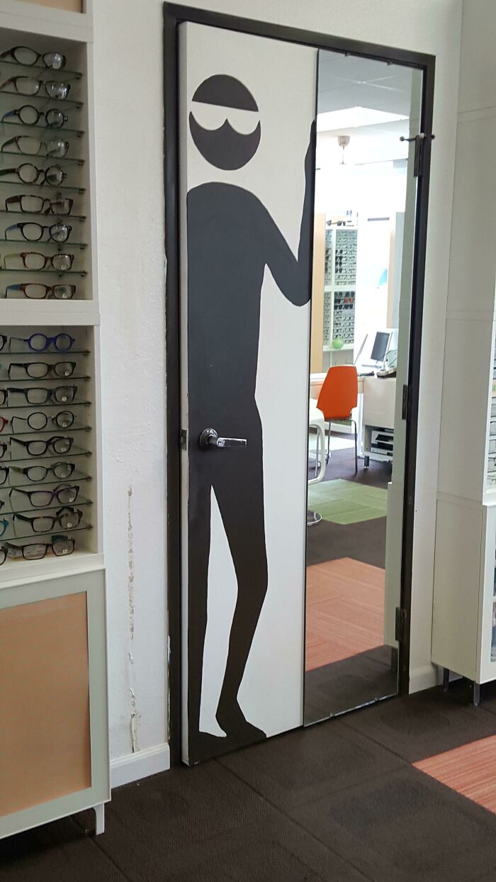 A door with a tall silhouette of a person wearing sunglasses, a design fail by the designers.