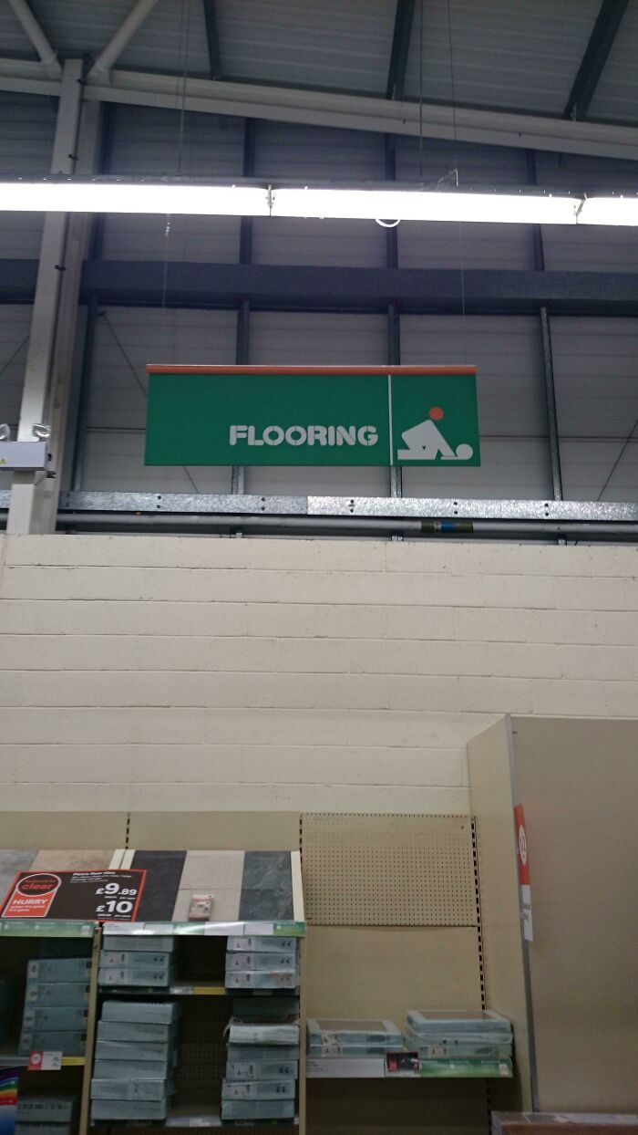 A store sign for FLOORING with a graphic resembling a person bending over, showcasing designers failing.