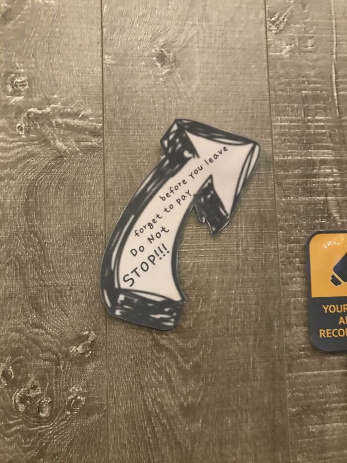 A hand-drawn arrow on the floor points away, with text telling people not to forget to pay, illustrating designers failing.
