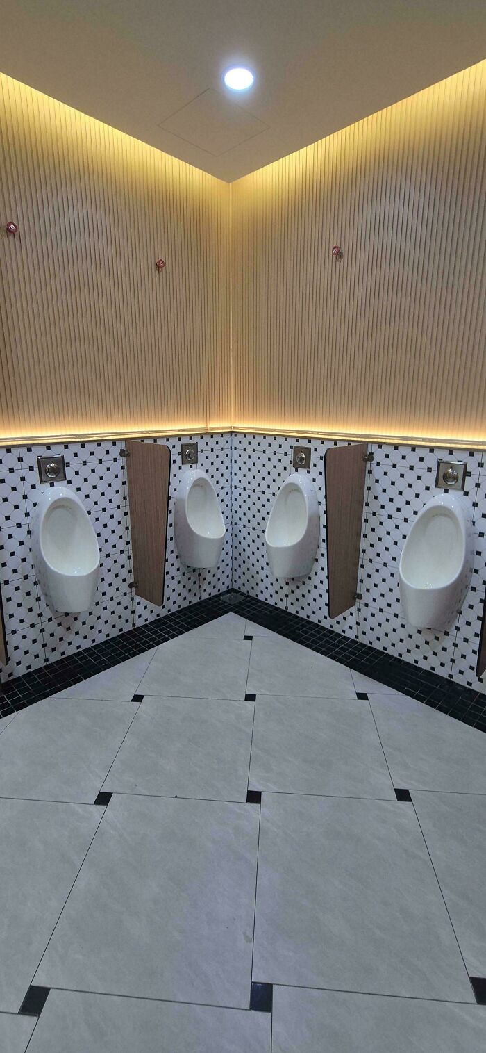 Four urinals are installed in a tight corner of a men's restroom, making them unusable due to a design fail.