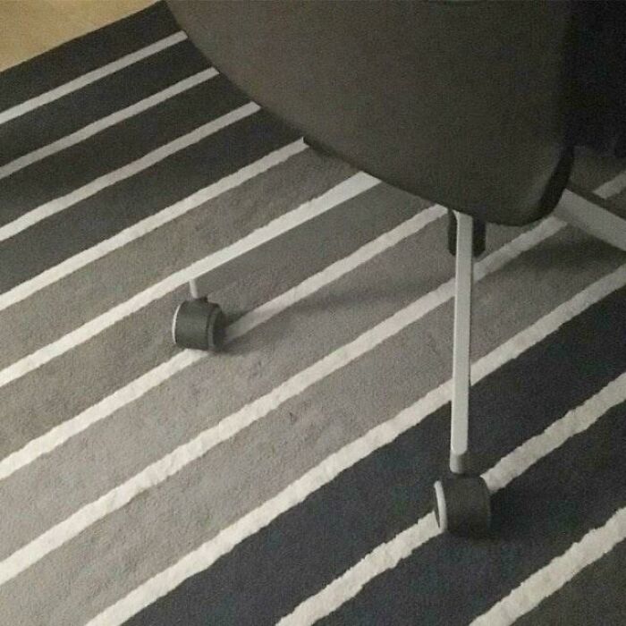 An optical illusion of a chair wheel blending into a striped rug.