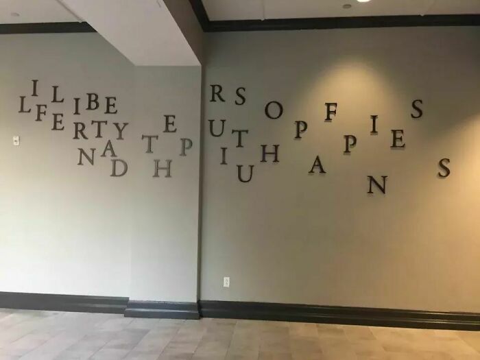 Wall art with scrambled letters that are hard to read, demonstrating a designer's failure.