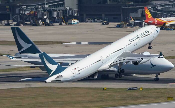 A large Cathay Pacific airplane on the tarmac, with an extreme angle that looks like an optical illusion.