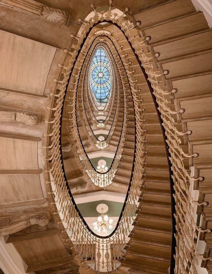 Intricate spiral staircase showcasing beautiful architecture with a stained glass skylight.
